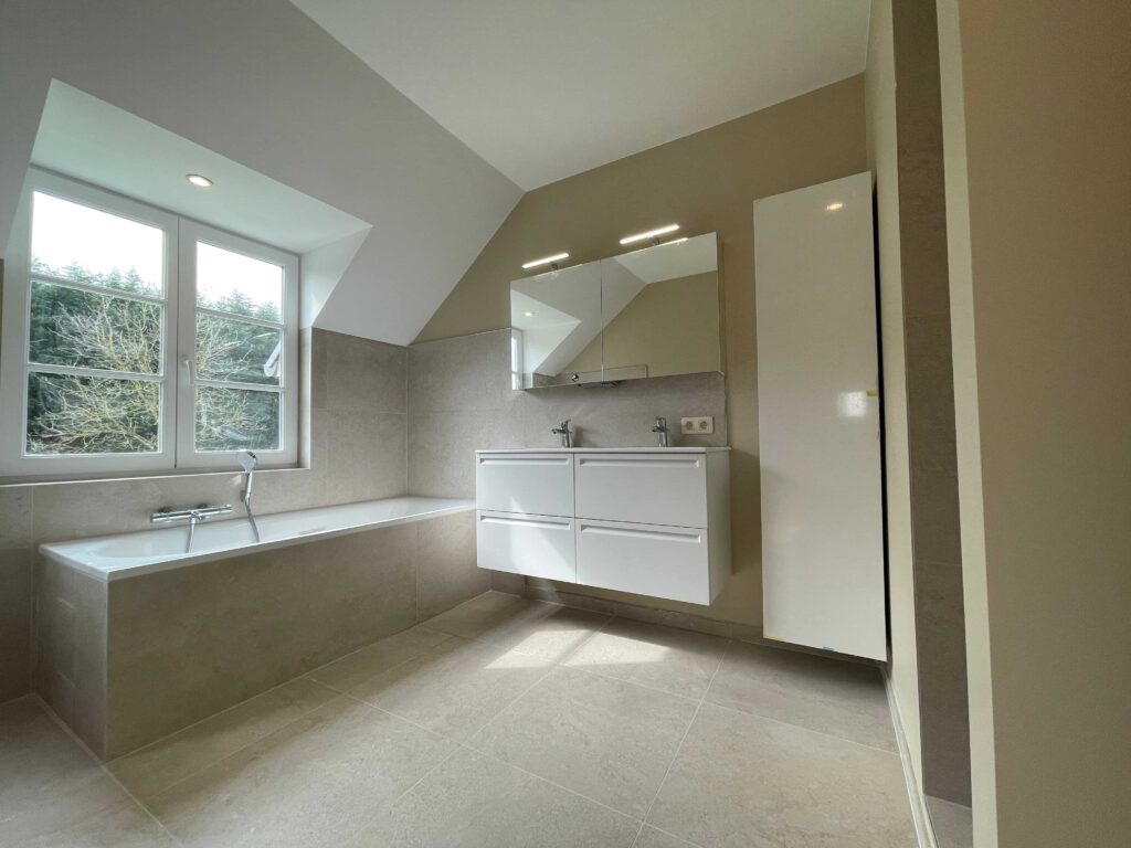 “Rénovation de salle de bain à Ixelles (Bruxelles) avec baignoire, carrelage grand format et meuble vasque blanc.”